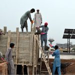 Construction workers build a reinforced concrete water tank on the rooftop of an under-construction building in the Federal Capital