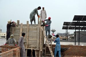 Construction workers build a reinforced concrete water tank on the rooftop of an under-construction building in the Federal Capital