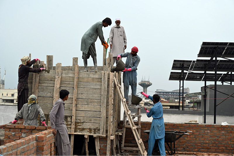 Construction workers build a reinforced concrete water tank on the rooftop of an under-construction building in the Federal Capital