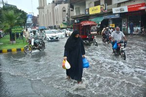 A veiled woman crosses a waterlogged road after heavy monsoon rain, as poor drainage caused flooding in parts of the city.