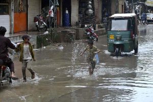 Motorcyclists navigate a flooded road following a torrential monsoon rain spell at Imam bara chowk in the twin cities