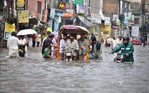 Motorcyclists navigate a flooded road following a torrential monsoon rain spell at Imam bara chowk in the twin cities
