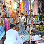 Customers select and purchase fancy clothes at a shop in the weekly Sunday Bazaar near Peshawar Morr in the Federal Capital