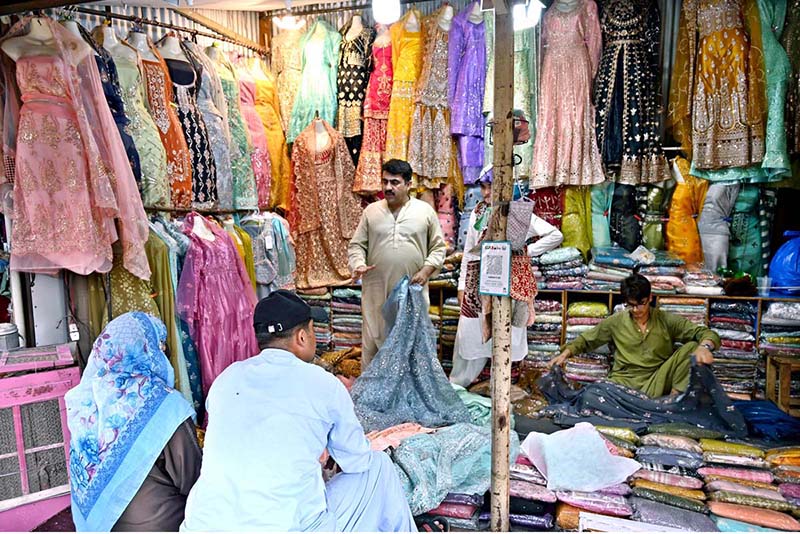 Customers select and purchase fancy clothes at a shop in the weekly Sunday Bazaar near Peshawar Morr in the Federal Capital