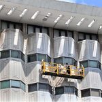 Workers suspended on a hanging scaffold carry out cleaning and maintenance of the iconic WAPDA House building