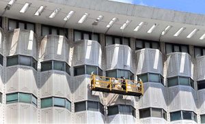Workers suspended on a hanging scaffold carry out cleaning and maintenance of the iconic WAPDA House building