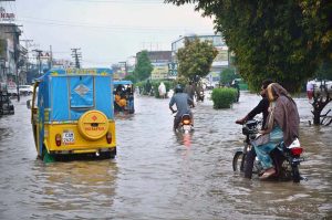 A veiled woman crosses a waterlogged road after heavy monsoon rain, as poor drainage caused flooding in parts of the city.