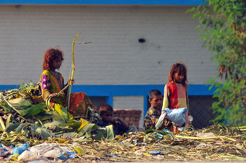 Gypsy children search for recyclable and valuable items in a roadside garbage heap near Vehari Chowk to earn a livelihood in the city