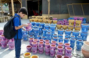 A youngster shows keen interest while looking at colourful traditional clay pots displayed at a pottery market.