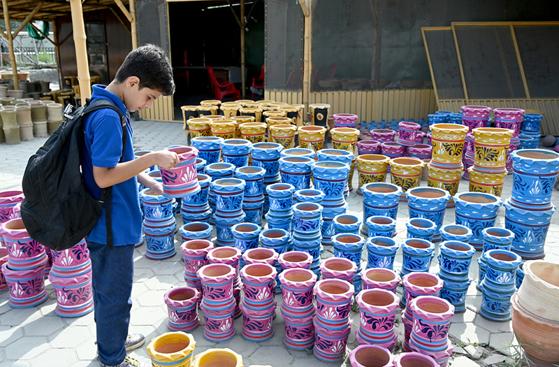 A youngster shows keen interest while looking at colourful traditional clay pots displayed at a pottery market.