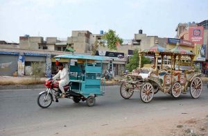A tricycle rickshaw driver on the way while tows a buggy (decorated horse cart) at Sheikhupura Road.