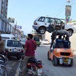 Traffic police use a forklift to remove an illegally parked vehicle from the roadside as part of an anti-encroachment operation