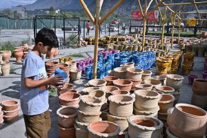A youngster shows keen interest while looking at colourful traditional clay pots displayed at a pottery market.