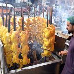A vendor roasts chickens on skewers over an open flame at his roadside stall along Saidpur Road in the city