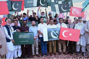 Civil society representatives and citizens raise the flags of Pakistan, Saudi Arabia and Türkiye during a ceremony organized by the district administration at Gulshan-e-Iqbal Park to celebrate the Mecca Defence Agreement among the three countries