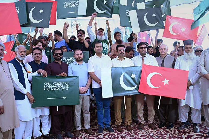 Civil society representatives and citizens raise the flags of Pakistan, Saudi Arabia and Türkiye during a ceremony organized by the district administration at Gulshan-e-Iqbal Park to celebrate the Mecca Defence Agreement among the three countries