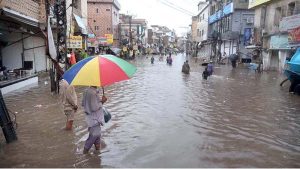 A child stands amid floodwater as an auto-rickshaw makes its way through the inundated street following heavy monsoon rains in Dhoke Khabba