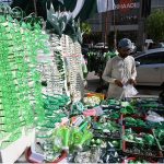 A vendor displays Pakistani flags, badges, headbands and other Jashn-e-Azadi items at a roadside stall near Commercial Market as shoppers browse the festive merchandise ahead of Independence Day celebrations