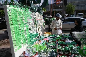 A vendor displays Pakistani flags, badges, headbands and other Jashn-e-Azadi items at a roadside stall near Commercial Market as shoppers browse the festive merchandise ahead of Independence Day celebrations