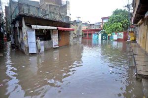 A child stands amid floodwater as an auto-rickshaw makes its way through the inundated street following heavy monsoon rains in Dhoke Khabba