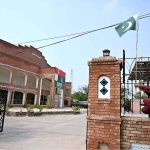 A man installs Pakistani national flags on the Arts Council building ahead of Independence Day celebrations
