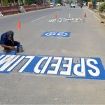 A worker paints road signs along Jail Road as part of routine maintenance work in the city