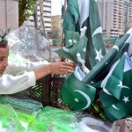 A girl vendor arranges Pakistani national flags in a basket to attract customers ahead of Independence Day celebrations