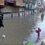 People wade through floodwater as rainwater enters buildings and shops following torrential monsoon rains in Amarpura in twin cities