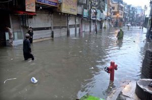 People wade through floodwater as rainwater enters buildings and shops following torrential monsoon rains in Amarpura in twin cities