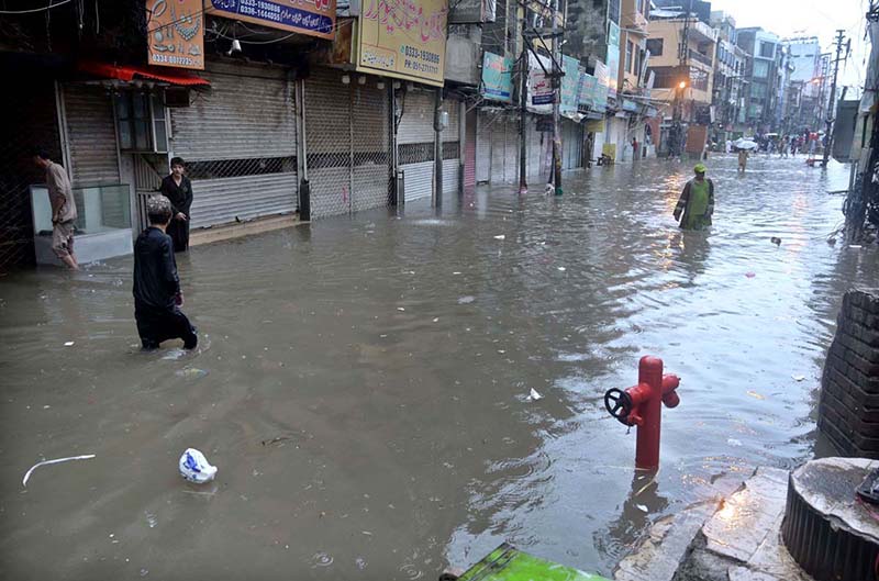 People wade through floodwater as rainwater enters buildings and shops following torrential monsoon rains in Amarpura in twin cities