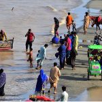 People spending time along the banks of the Indus River for recreation as water levels rise following heavy monsoon rains across the country