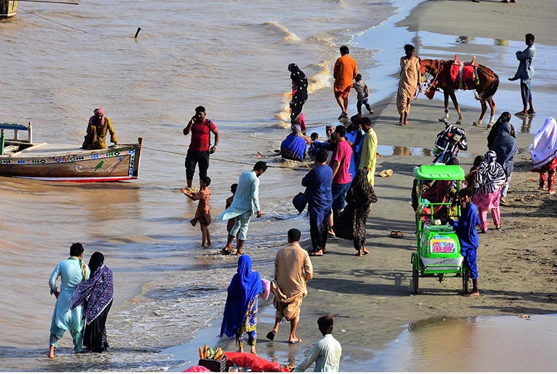 People spending time along the banks of the Indus River for recreation as water levels rise following heavy monsoon rains across the country