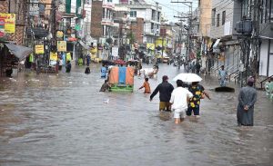 People wade through floodwater as rainwater enters buildings and shops following torrential monsoon rains in Amarpura in twin cities