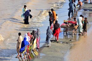 People spending time along the banks of the Indus River for recreation as water levels rise following heavy monsoon rains across the country