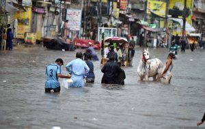 People wade through floodwater as rainwater enters buildings and shops following torrential monsoon rains in Amarpura in twin cities