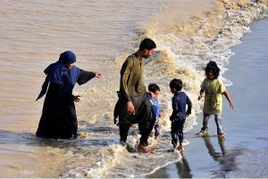 People spending time along the banks of the Indus River for recreation as water levels rise following heavy monsoon rains across the country