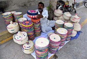 A roadside vendor displays and sells handcrafted palm-leaf baskets and household items along Government Girls Degree College Road in the city.