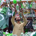 Vendors display National flags ,Pakistan-themed bands, toys and decorative items at a roadside stall ahead of Independence Day celebrations at Qissa Khawani Bazaar