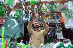 Vendors display National flags ,Pakistan-themed bands, toys and decorative items at a roadside stall ahead of Independence Day celebrations at Qissa Khawani Bazaar