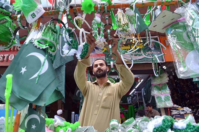 Vendors display National flags ,Pakistan-themed bands, toys and decorative items at a roadside stall ahead of Independence Day celebrations at Qissa Khawani Bazaar