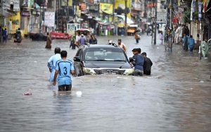 People wade through floodwater as rainwater enters buildings and shops following torrential monsoon rains in Amarpura in twin cities