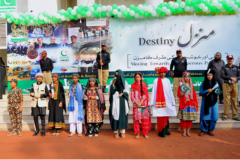 Children dressed in traditional attire and holding national flags participate in a ceremony to mark Pakistan’s 79th Independence Day in the city