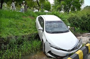 A car slips from a parking area and falls into a roadside drain in front of the Excise Office