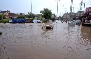 People wade through floodwater as rainwater enters buildings and shops following torrential monsoon rains in Amarpura in twin cities