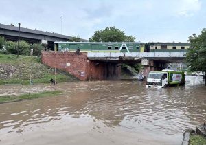 Train passes over a bridge as vehicles lie stranded in deep floodwater below, following heavy monsoon rain at Rahimabad area in the City.
