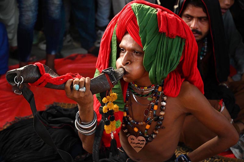 A devotee (malang) performing musical instrument Bigul at outside the Data Darbar while a large number of people arrives to attend the three day 983Urs celebration of renowned Sufi Data Gunj Buksh