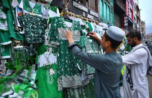 A vendor displays Pakistan Independence Day-themed children dresses, shirts at a roadside stall in Qissa Khawani Bazaar ahead of the country's 79th Independence Day celebrations.
