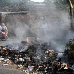 People rides past as smoke billows from a burning garbage dump in residential areas Railway Colony posing a serious threat to human health and the environment ,to attention the concern authorities
