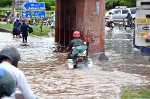 Train passes over a bridge as vehicles lie stranded in deep floodwater below, following heavy monsoon rain at Rahimabad area in the City.