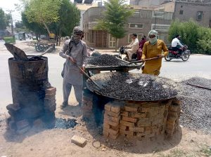 Construction workers mix hot asphalt (tar), crushed stone and gravel to prepare road surfacing material during an ongoing road development project aimed at improving the city's transport infrastructure.